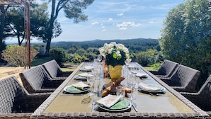 A dining table set outdoors with a view of a forest and hills in the background. - Charming 5 bedroom, 3 bathroom Villa in gated domain near Valbonne with sea view (Opio)