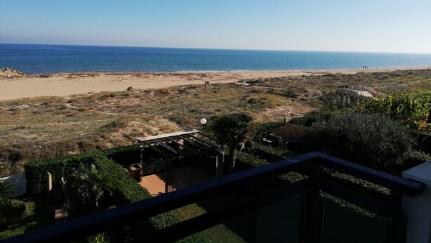 Blick auf einen Strand von einem Balkon bei blauem Himmel.