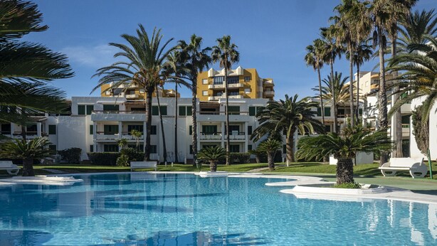 A hotel with a pool surrounded by palm trees and a clear blue sky. - Deltamar 24 Solo Familias! (Xeraco Playa)