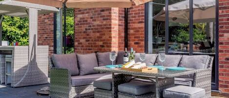 A patio with wicker furniture, a table, and a large umbrella.