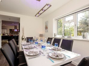 A dining area with a long table set for six, equipped with plates, glasses, and cutlery. - Kingfisher Lodge (Norwich)