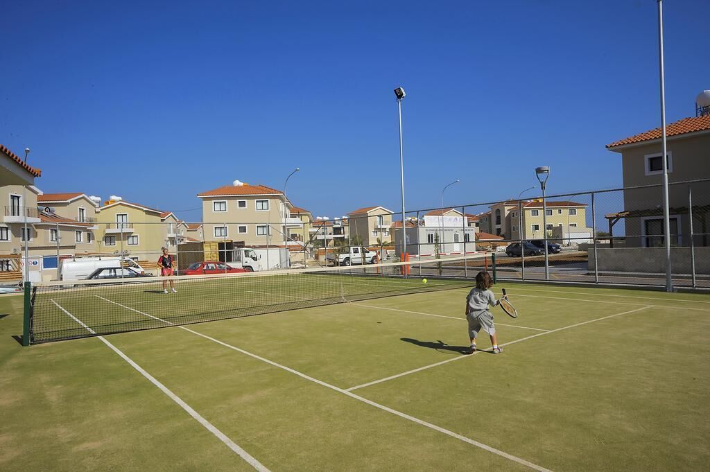 A tennis court with a net, surrounded by residential buildings.