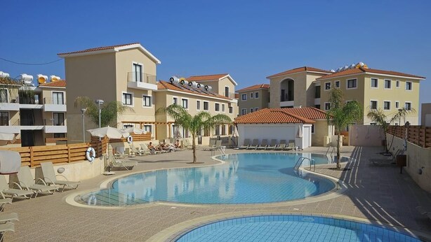 A swimming pool area with multiple buildings, some with balconies and others with terraces. - Luxurious Unique Apartment (Paralimni)