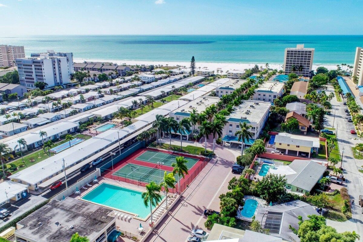 Un hôtel situé sur la côte, composé de plusieurs bâtiments, doté d’un court de tennis et d’une piscine.