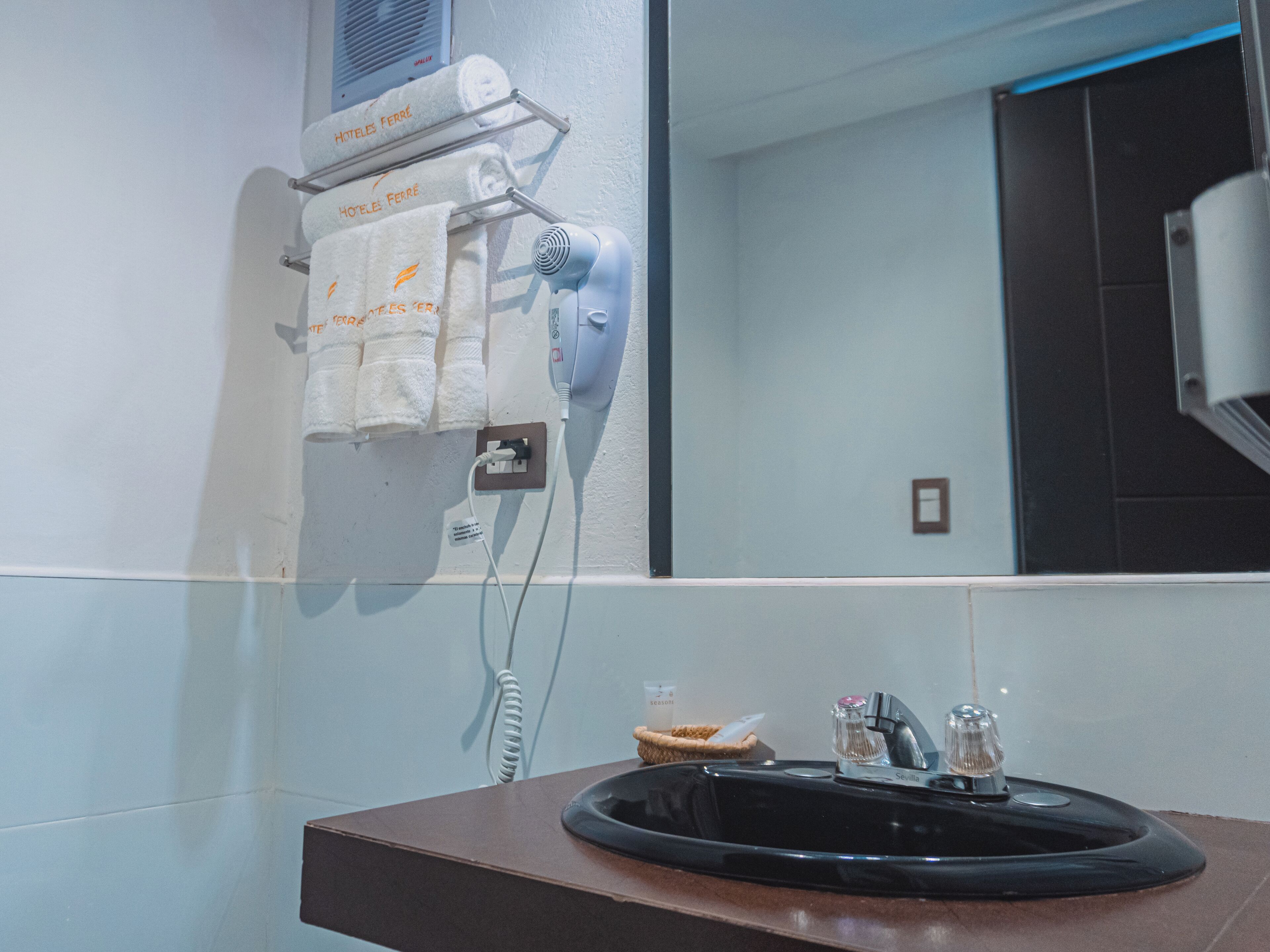 A bathroom with a sink, mirror, towel rack, and hairdryer.