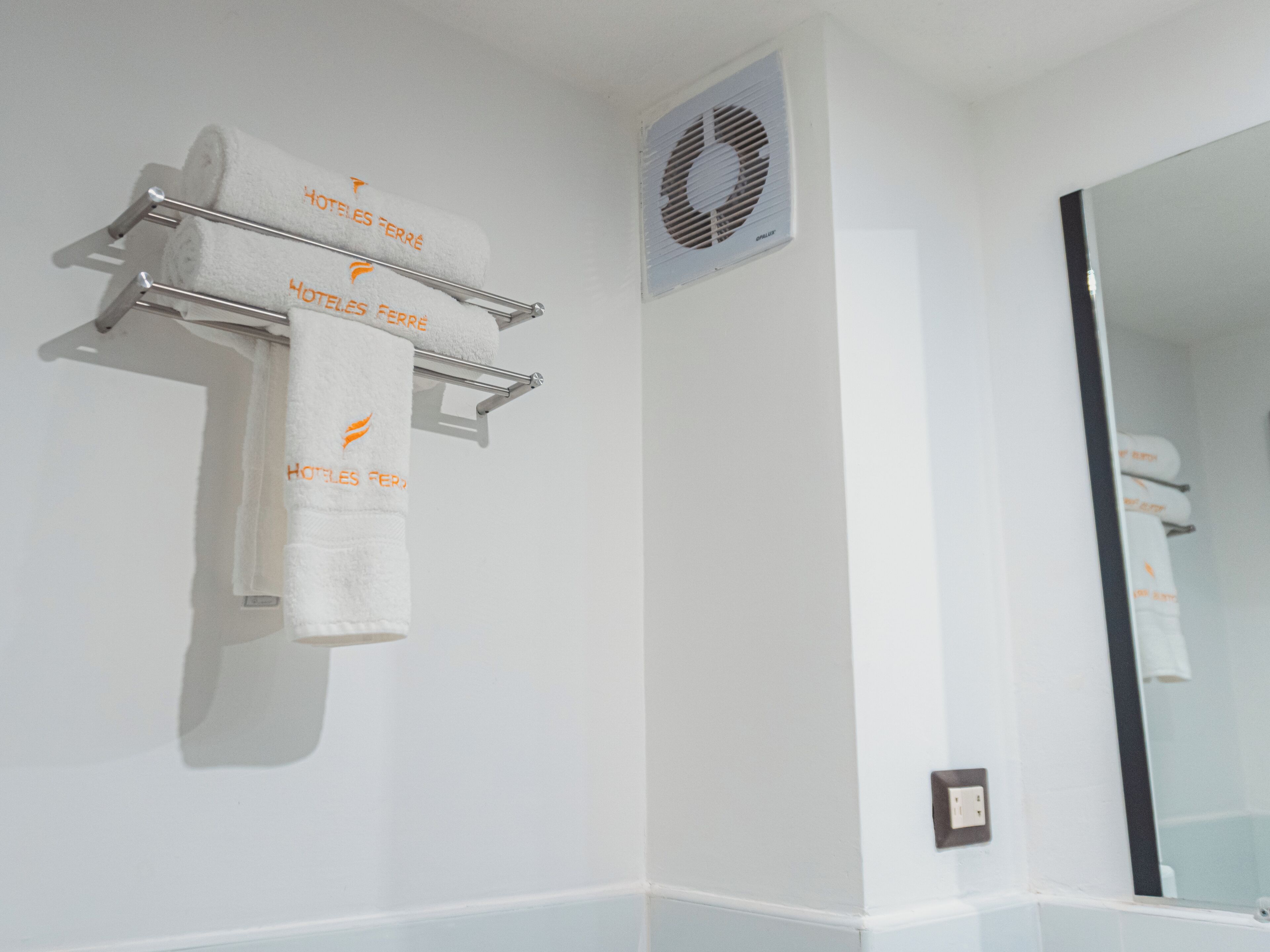 A bathroom with a towel rack holding two towels, a vent, and a mirror.