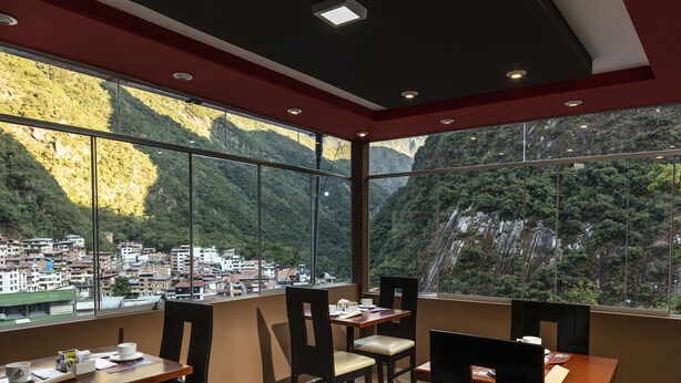 Un espace repas offrant une vue sur une ville de montagne grâce à de grandes fenêtres.