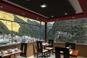 Un espace repas offrant une vue sur une ville de montagne grâce à de grandes fenêtres.