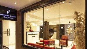 L’intérieur d’un hôtel, avec un comptoir d’accueil, un espace salon et un escalier.