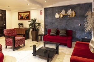 Un salon moderne avec un canapé rouge, des fauteuils à motifs, une table basse et des œuvres d’art décoratives accrochées au mur.