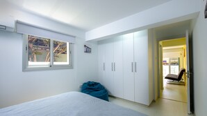 Et soveværelse med seng, vindue, garderobe og en oppustelig stol.