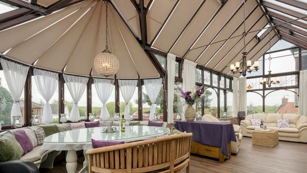 Une pièce spacieuse aménagée comme une tente, avec une table en verre, des chaises en bois et un canapé.