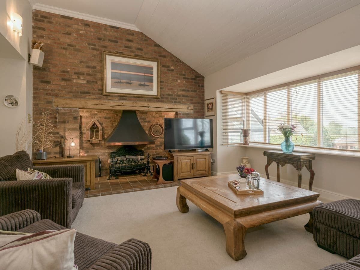 A cozy living room with a brick fireplace, a television, and comfortable seating.