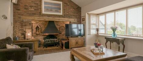 A cozy living room with a brick fireplace, a television, and comfortable seating.