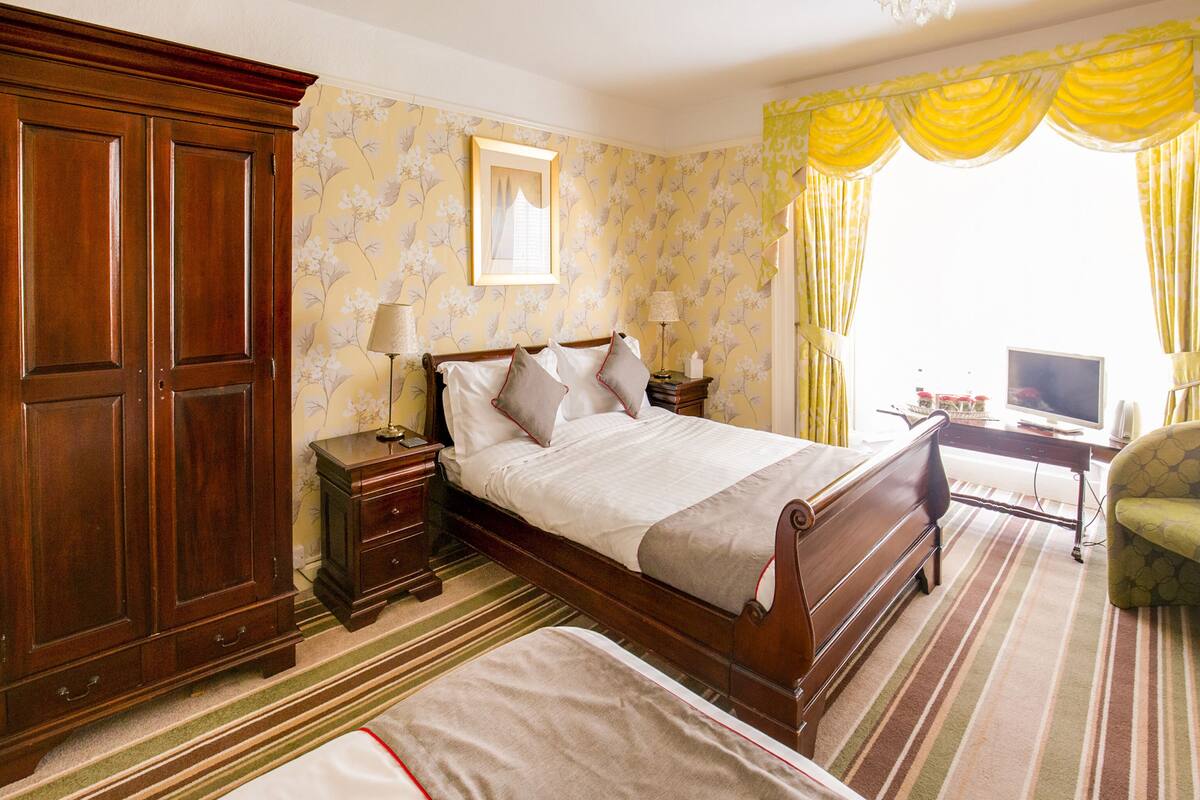 A hotel room with a large bed, a desk with a computer, and a wardrobe.