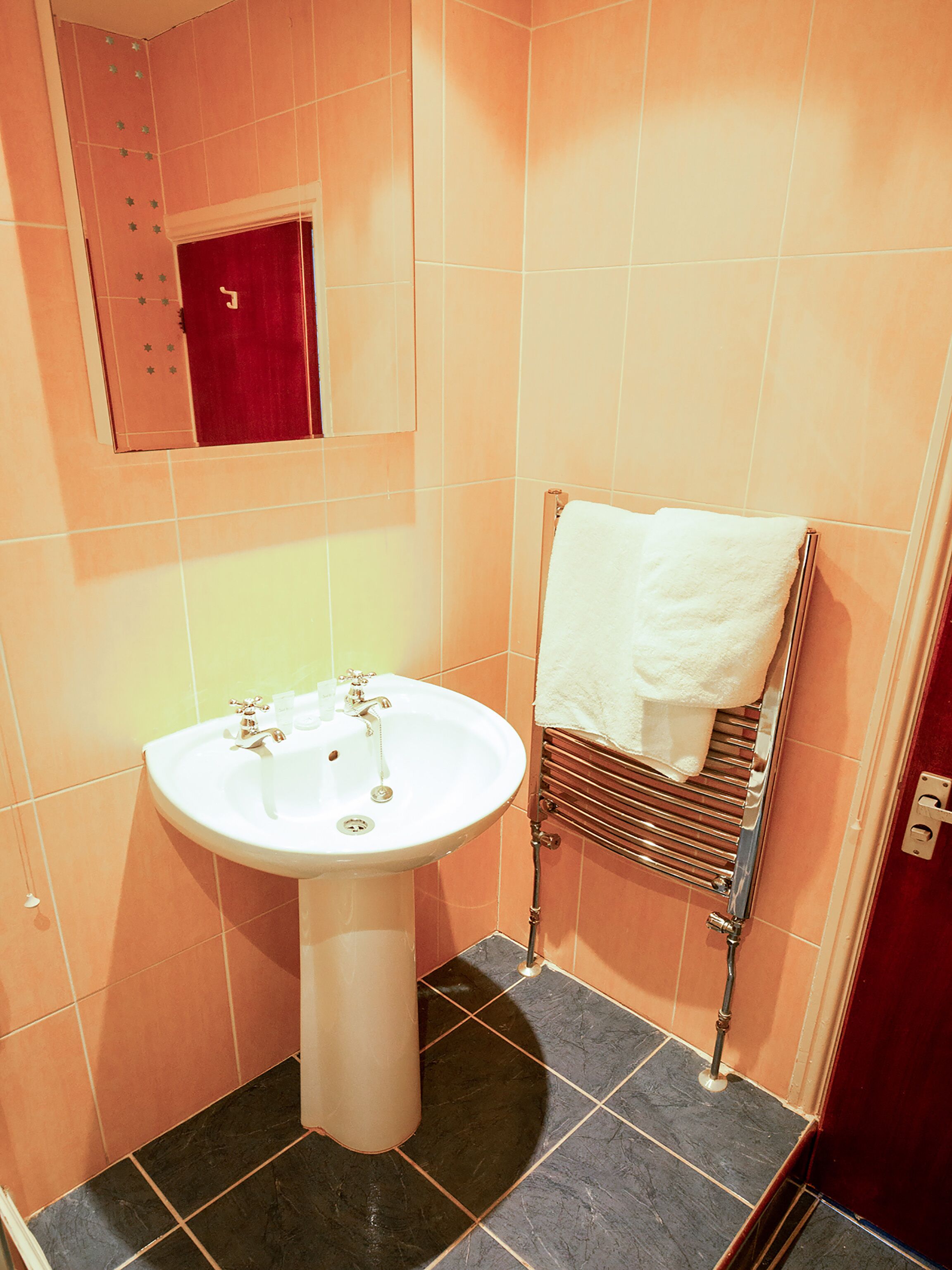 Een badkamer met een wit wastafelmeubel, een spiegel en een handdoekrek met een witte handdoek.