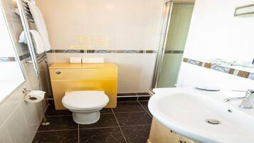 Une salle de bain comprenant des toilettes, un lavabo et un espace douche.