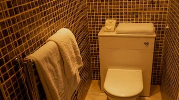 A bathroom with a tiled floor, a toilet, and a towel rack with a towel.