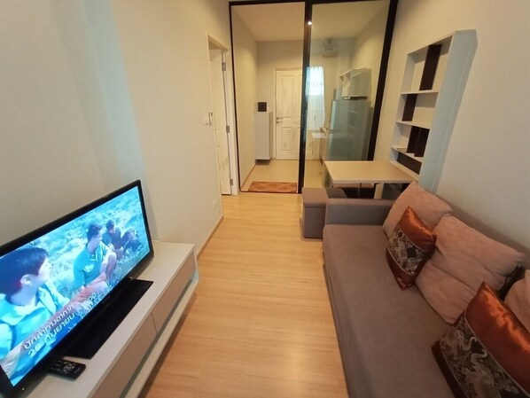 A modern living room with a flat-screen TV, a sofa, and a dining area.