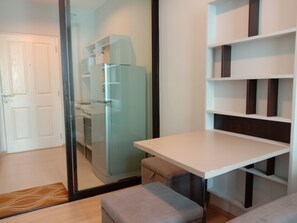 A modern kitchen with a refrigerator, a dining table, and a bench.