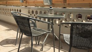 A terrace with wicker chairs and a small round table, a wooden fence, and potted plants. - Unique 2 bedroom modern apartment (Ayia Napa)
