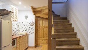 A kitchen with wooden cabinets, a tiled backsplash, and a wooden staircase leading to an upper level. - Willa Ślimakówka (Zakopane)