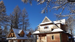 A wooden cabin with a balcony, a staircase, and a snow-covered roof. - Willa Ślimakówka (Zakopane)