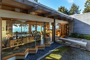 A modern house with large glass windows, a stone pathway, and a view of the ocean. - Sanctuary House - Architectural Gem w/ Ocean Views! (Trinidad)