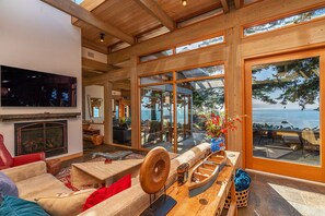 A spacious living area with a fireplace, comfortable seating, and large windows offering a view of the ocean. - Sanctuary House - Architectural Gem w/ Ocean Views! (Trinidad)