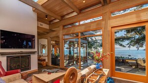 A spacious living area with a fireplace, comfortable seating, and large windows offering a view of the ocean. - Sanctuary House - Architectural Gem w/ Ocean Views! (Trinidad)
