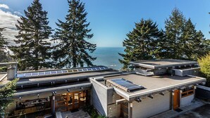 A modern house with a flat roof, solar panels, and a view of the ocean. - Sanctuary House - Architectural Gem w/ Ocean Views! (Trinidad)