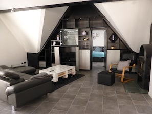 Un espacio habitable compacto con sofá, mesa de centro, silla y zona de kitchenette.
