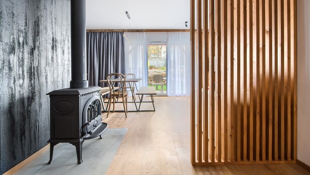 Une pièce avec une cheminée, un plancher en bois et une vue par la fenêtre.
