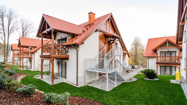Ein modernes Gebäude mit rotem Ziegeldach, hölzernen Balkonen und einer zentralen Treppe.