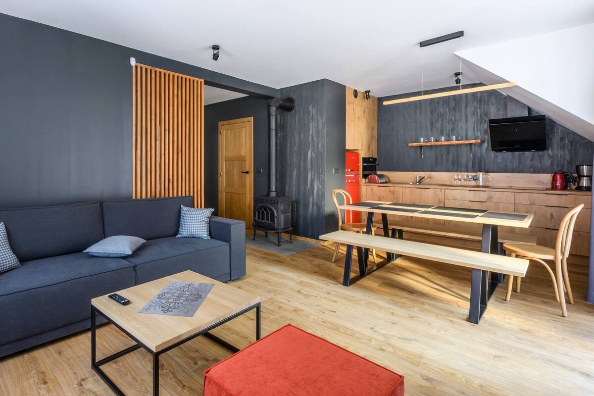 Een moderne woonkamer met een bank, salontafel en een eethoek met een tafel en stoelen.
