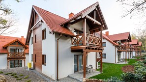 Ein modernes, zweistöckiges Haus mit Balkon, Ziegeldach und gepflegtem Garten.