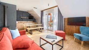 Un salon moderne avec un canapé, une table basse et un téléviseur. Il y a également un coin cuisine avec des meubles en bois et une table à manger.