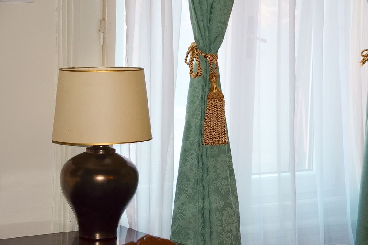 Una lámpara con pantalla color crema y base oscura sobre una mesa.