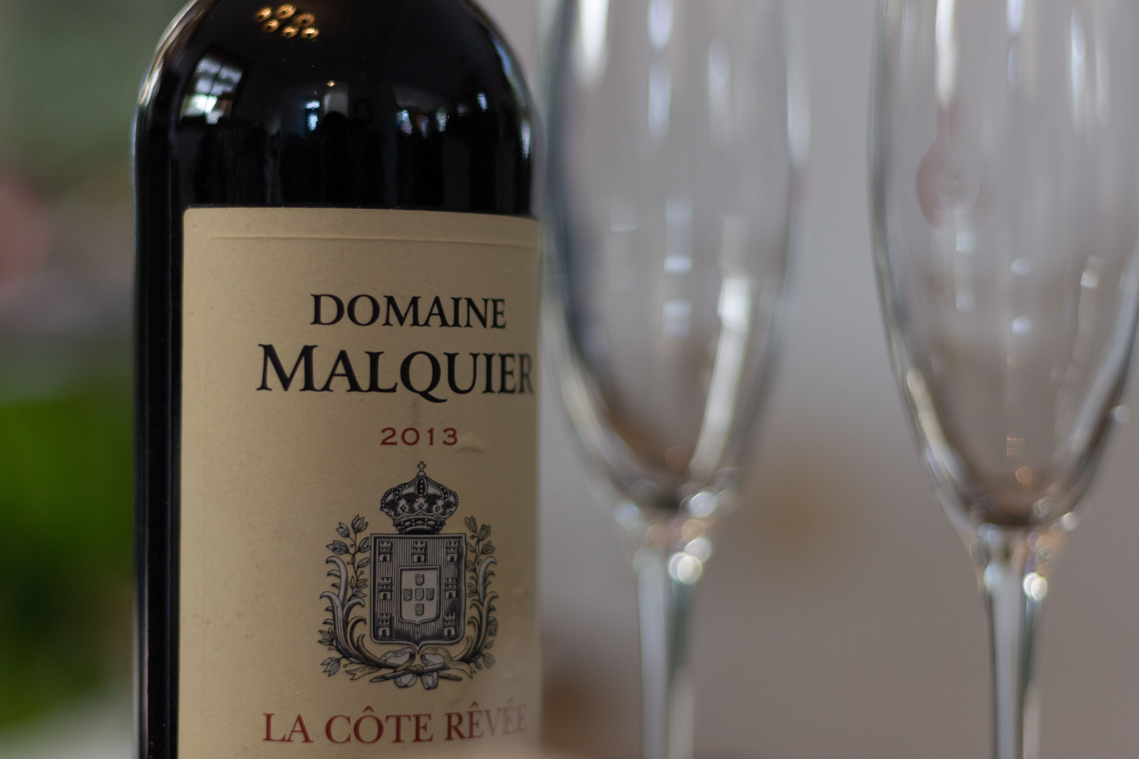 A bottle of Domaine Malquois wine from 2013 with a label featuring a coat of arms.