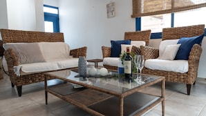 A room with wicker furniture, a glass coffee table, and a bottle of wine. - Villa Near the Beach (Paralimni)