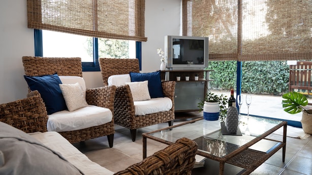 A living room with wicker furniture, a glass coffee table, and a television. - Villa Near the Beach (Paralimni)