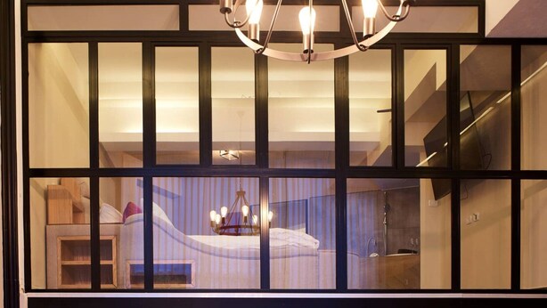 Un interior modern amb un finestral gran, una làmpada de cristall i una escala.
