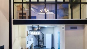 Un interior modern amb zona de menjador, escala i saló.