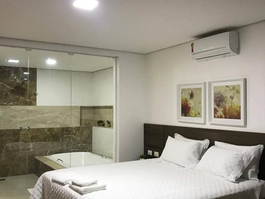 Un dormitorio moderno con una cama grande, cabina de ducha de vidrio y aire acondicionado instalado.