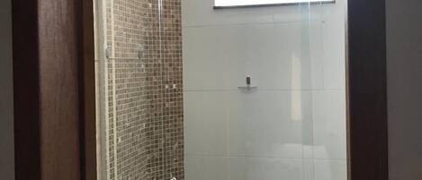 A glass-enclosed shower area with a tiled wall and a small window.