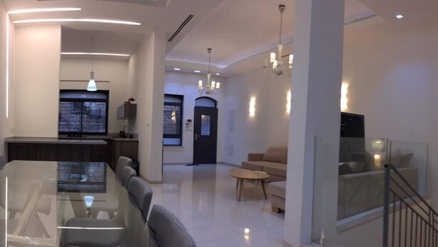 Ein modernes Wohnzimmer mit einem Glastisch, Sofas und einer Treppe.