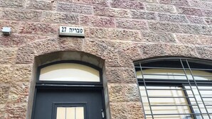 Ein Steinhaus mit einer schwarzen Tür und einem Fenster mit einem Metallgitter.