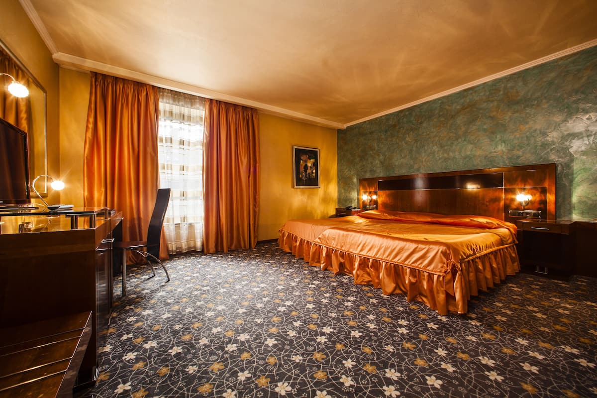 Een hotelkamer met een groot bed, een bureau met een spiegel en een kast.