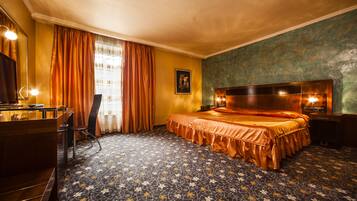 A hotel room with a large bed, a desk with a mirror, and a dresser.