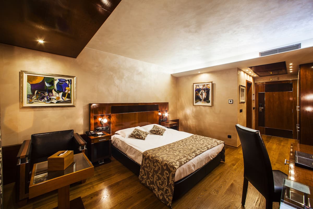 Een hotelkamer met een groot bed, een bureau, een stoel en kunstwerken aan de muren.